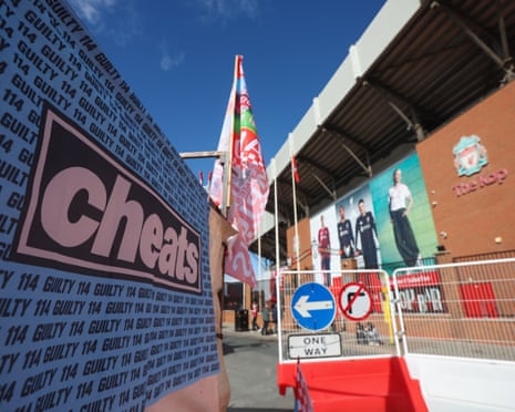 An exterior view of Anfield with a banner reading "Cheats" and "114 guilty" in Manchester City colours