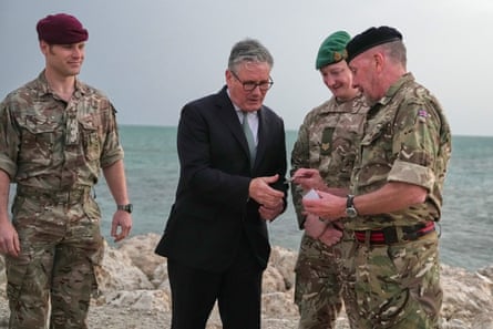 Starmer standing with three men in army fatigues on a beach