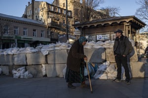 An elderly woman walks pass concrete blocks topped with sandbags at a street in Odesa, southern Ukraine, on Tuesday