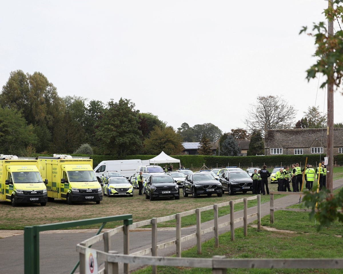 Ambulances and police cars parked on a village green.