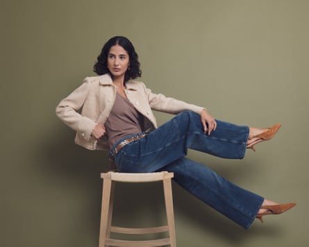 seated female model wearing beige Jacket, baggy jeans and brown suede slingbacks