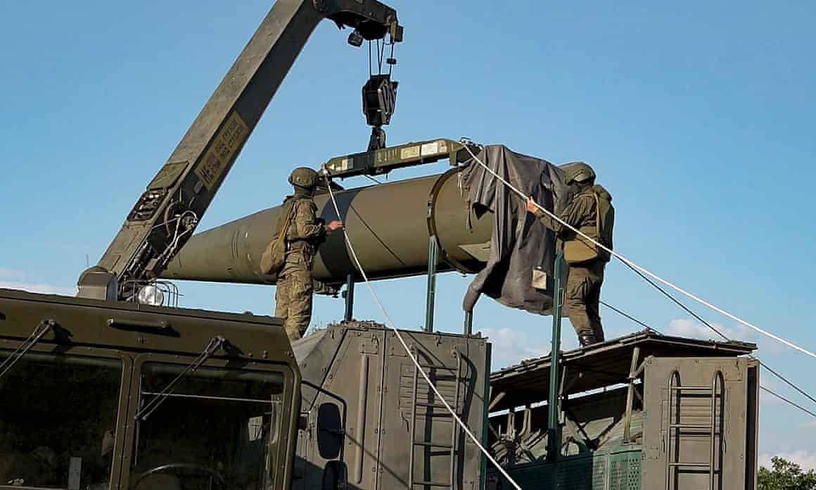 Two soldiers preparing large missile amid blue sky