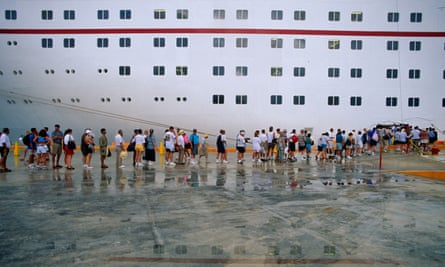 A queue of people waits to board a cruise ship
