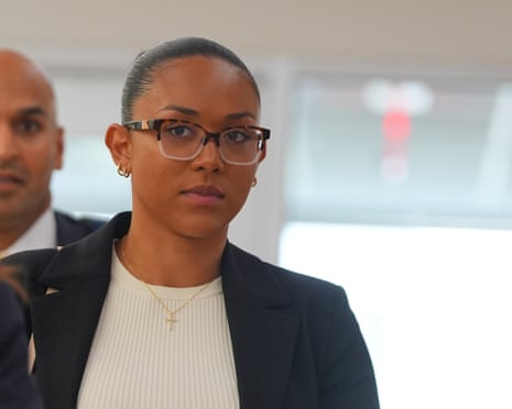McKenna West, wearing glasses and a dark blazer, walks in a courthouse hallway