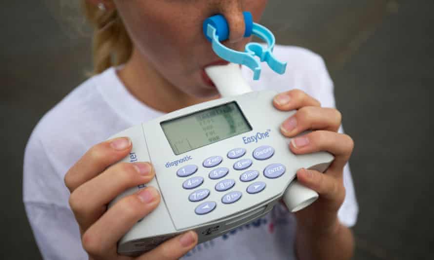 A woman blows into a spirometer