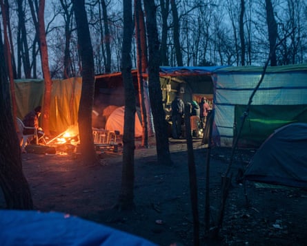a make shift camp and campfire in the woods in the dark