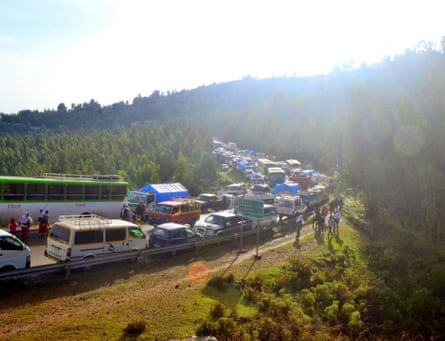 People stand around their cars, which are backed up along a closed road in rural Ethiopia