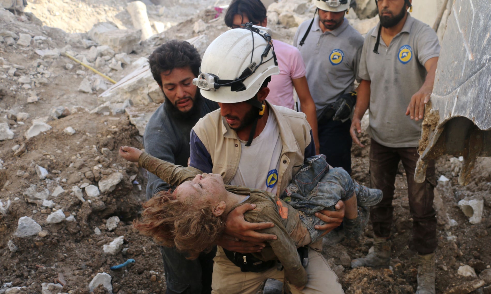 A member of the White Helmets, also known as the Syrian civil defence, holds a child pulled from the rubble following an airstrike in Aleppo in 2016.