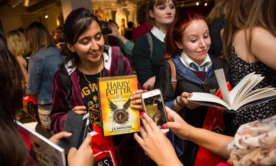 Customers take photos after buying a copy of JK Rowling’s Harry Potter and The Cursed Child a little after midnight at Foyles book store in London.