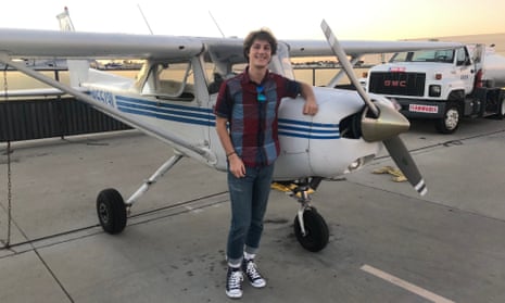 Portrait of a young man smiling while leaning one arm on a small prop plane.