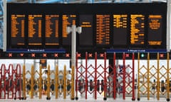 temporary yellow barriers cordon off the platform gates at waterloo beneath the huge black and gold electronic info board.