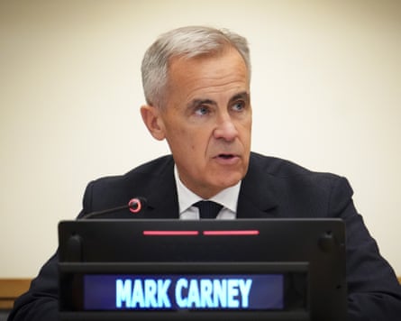 Mark Carney behind a desk bearing his name