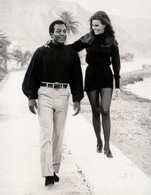 Jim Brown and Raquel Welch take a break during the filming of 100 Rifles on a shoreline road near Almeria, Spain in 1969.