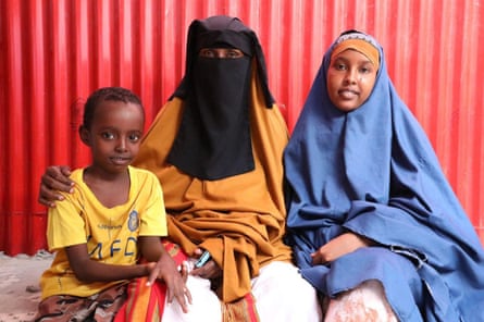 A female successful a achromatic niqab veil against a reddish metallic inheritance pinch 2 children – a boy successful a T-shirt and a woman successful a chador-type afloat veil