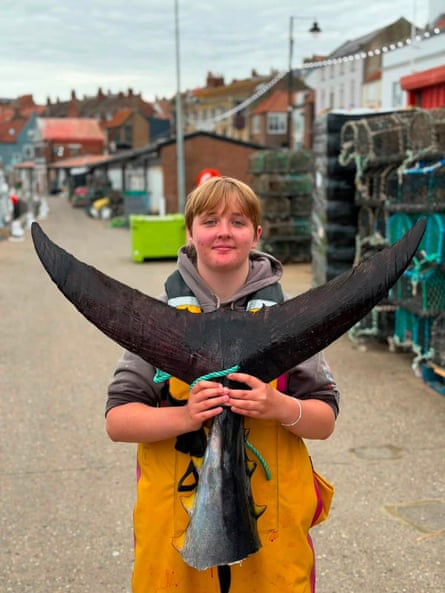 A young woman holds the tail of the giant bluefin tuna