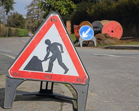 A contractors roadworks warning sign in a rural residential street. Keep left sign and reels of cable in the background<br>EK68G9 A contractors roadworks warning sign in a rural residential street. Keep left sign and reels of cable in the background