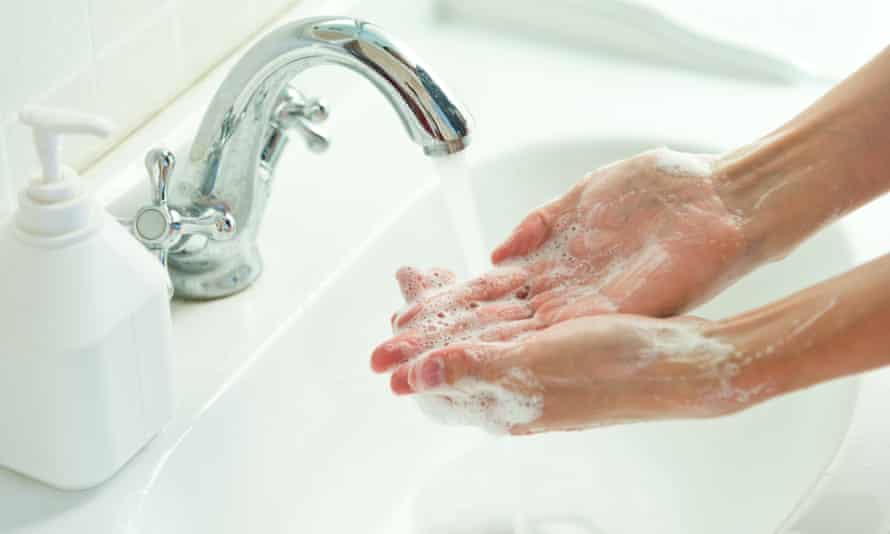 Woman washing her hands with soap and water at a sink
