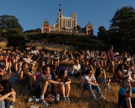 People gather to view the partial solar eclipse in Greenwich Park in London, United Kingdom.