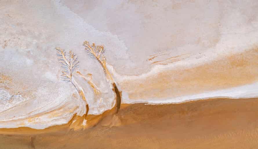 North Lake Eyre edge showing water (brown), salt pan and water flow patterns. Lake Eyre North, South Australia, Australia March 2022