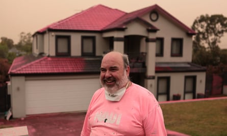 Douglas Greening stands outside his neighbour’s house, covered in fire retardant dropped from aircraft on Canoon Road, South Turrumurra