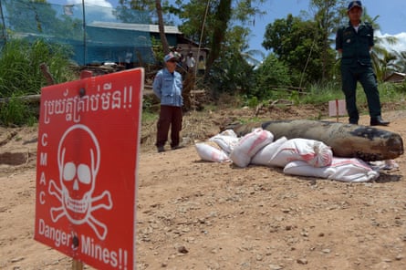 A Cambodian mine action centre member, left, and policeman keep watch behind a Mark 82 bomb in Kandal province.