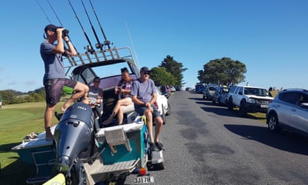 John Fitzgerald, left, on holidays with his wife Rita and friends, scans the horizon from high ground for any sign of a tsunami near Waitangi, New Zealand, Friday, March 5, 2021. A powerful magnitude 8.1 earthquake struck in the ocean off the coast of New Zealand prompting thousands of people to evacuate and triggering tsunami warnings across the South Pacific. (Peter De Graaf/New Zealand Herald via AP)