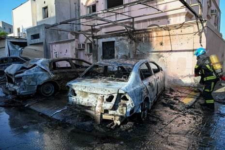 Firefighter working near burnt out cars.