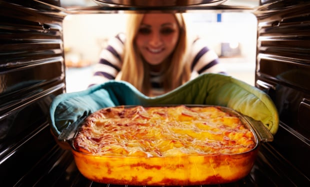 Woman taking lasagna from the oven
