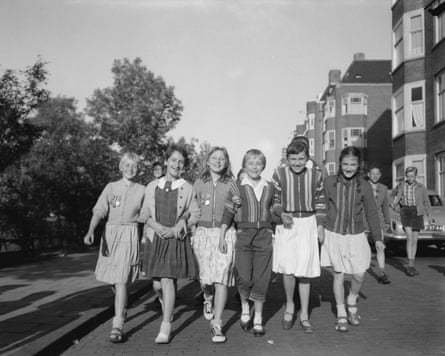 group of children walk along with armed linked