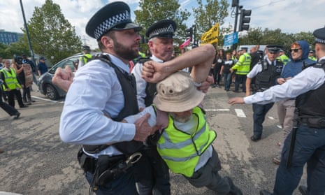 Police pull a protester off the road outside the DSEI exhibition