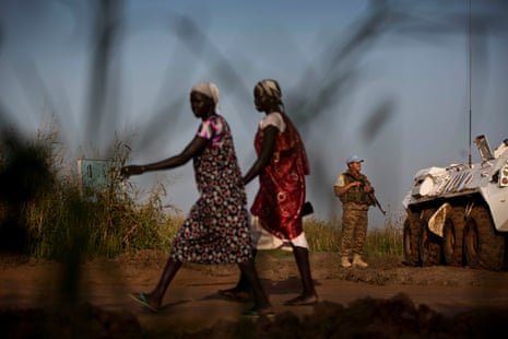 Two women walk past a UN peacekeeper outside the protection of civilian camp in Bentiu, South Sudan