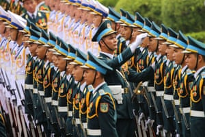 An officer adjusts the peaked cap of a soldier in the guard of honour