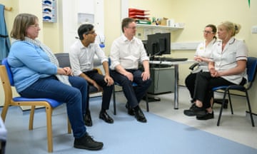 Rishi Sunak talks to healthcare professionals as he sits in a clinical room at a hospital