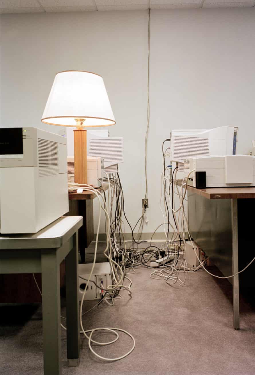 Desks in an office with wires hanging off them and a lamp on one
