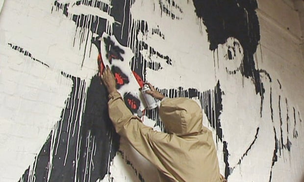 Artist purporting to be Banksy stencils a black insect on to a wall