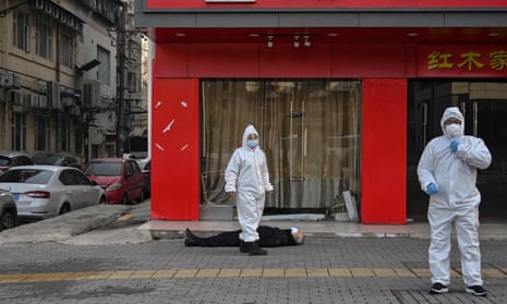 Emergency staff in protective suits check the body of a man who collapsed and died in the street in Wuhan on Thursday.