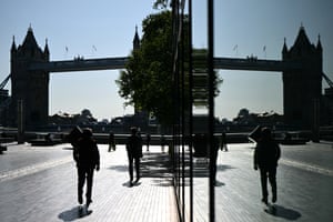 Much of Tower Bridge and number of people are mirrored in the windows of an adjacent building