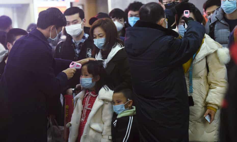 Staff check temperatures of the passengers arriving from Wuhan at Hangzhou railway station.
