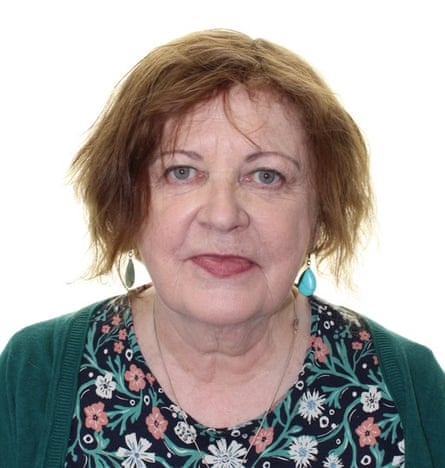 Deirdre O'Sullivan, a woman with reddish hair and turquoise earrings, smiles slightly for a portrait