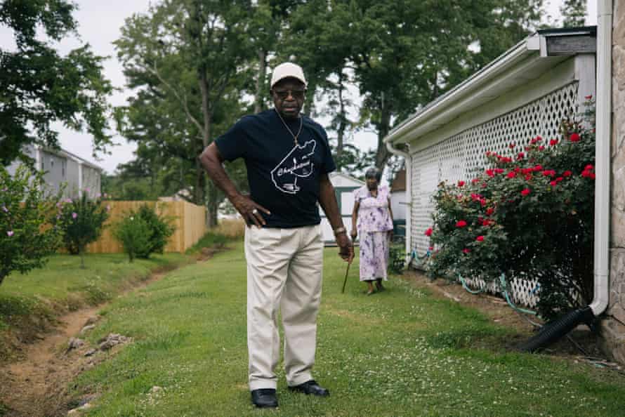 Roosevelt and Catherine Jones walk through their backyard, which floods whenever heavy rain falls in the town where the couple has lived their entire lives. On the left side of the frame is a ditch dug out to drain water away from their home.