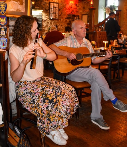 A woman playing flute and a man playing guitar in a restaurant and bar