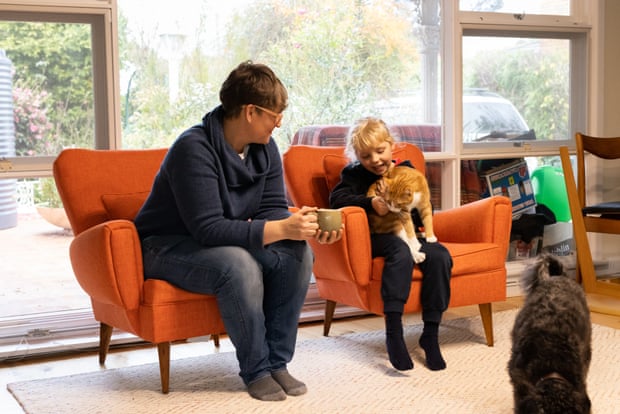 Jen Rae with her daughter Vivi Rae and cat Rocket and their dog Olive, sitting on orange armchairs