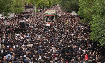 A large crowd tightly packed into a tree-lined street