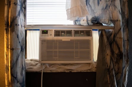 an air conditioning unit sits in a window with beige and blue curtains