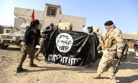 Iraqi soldiers hold up a captured Isis flag at a village near Mosul in 2016