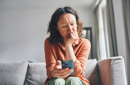 Concerned woman sitting on a sofa using a smartphone at home
