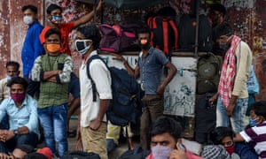 Os trabalhadores migrantes esperam na beira da estrada em 11 de junho para serem transferidos para uma estação ferroviária antes de embarcarem em trens especiais para os estados de Bihar e Jharkhand, na Índia, depois que o governo facilitou um bloqueio nacional.