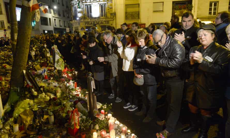 People applaud while uniting for a tribute at a makeshift memorial for the victims of a series of deadly attacks in Paris, near the “Belle Equipe” cafe on rue de Charonne in Paris on November 20, 2015.