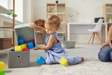 A young child putting toy cubes into a box