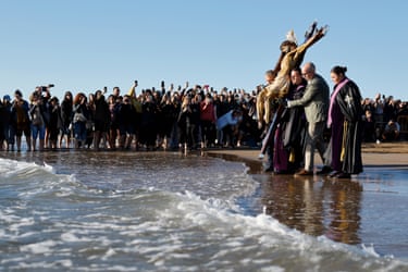 Image 26: The effigy is carried into the sea by a group surrounded by people taking photos